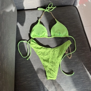Detail of neon green textured bikini with golden chain straps and ruched fabric finish