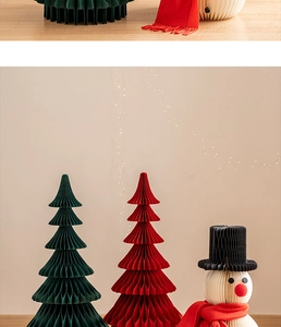 Close-up of honeycomb paper Christmas trees and snowman ornaments with warm fairy lights