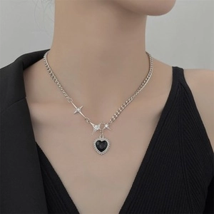 Detail of silver chain necklace with heart pendant and star charms on model