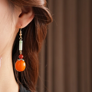 Detailed view of a Chinese-style persimmon earring with green jade and orange beads