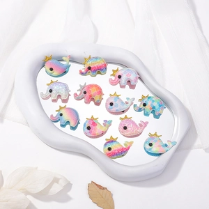 Close-up of glittery gradient hair clips featuring cartoon elephant and whale with crowns