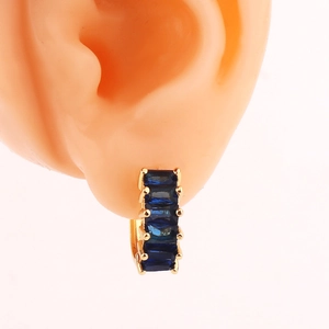 Detailed close-up of golden hoop earring with five rectangular blue gemstones on ear model
