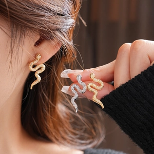 Détail des boucles d'oreilles serpent dorées et argentées serties de zircons brillants