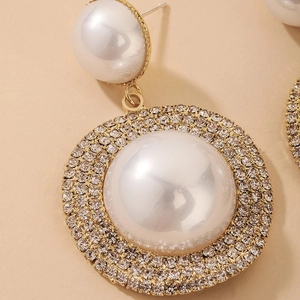Detailed close-up of luxury gold-tone drop earrings with pearls and sparkling rhinestones