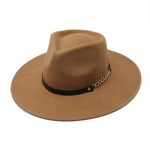 Dettaglio del cappello in feltro di lana cammello con nastro in pelle e catena oro