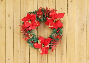 Close-up of a 40cm Christmas wreath with red poinsettias and pine cones on wood