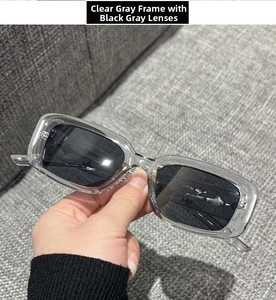 Detail of transparent grey rectangular sunglasses frame with dark grey lenses in hand