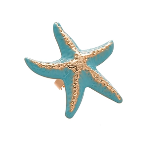 Golden starfish napkin ring with light blue enamel and textured grain on white background