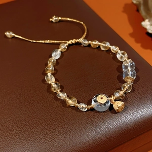Detailed close-up of citrine beaded bracelet with gold lotus pendant and coin charms