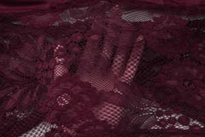 Detailed macro view of burgundy lace fabric showing floral pattern and transparency
