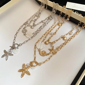 Detail of layered bohemian necklaces with starfish, shell charms and imitation pearls