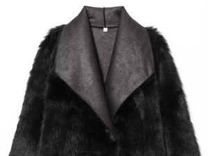Close-up of the black faux fur coat collar showing the XS size label and leather texture