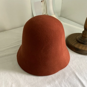 Gros plan du chapeau cloche en pure laine rouge rouille avec texture feutrée et élégante