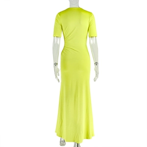Detail view of neon green pleated dress featuring side rushing and waist cut-out accents