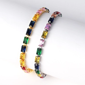 Close-up of colorful rectangular zircon bracelets in gold and silver finishes on a stand