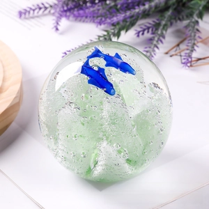 Close-up of a crystal glass sphere with blue dolphins and sea bubbles inside