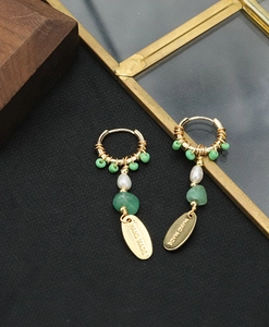 Detail of baroque pearl and green gemstone long earrings with engraved handmade tag