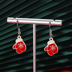 Detail of red Christmas glove earrings with white snowflakes hanging on a silver stand
