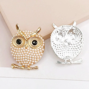 Golden owl jewelry accessory with white pearls and black eyes, showing front and back views