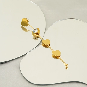 Elegant gold drop earrings with zircon hearts and mirrored reflections on gray background