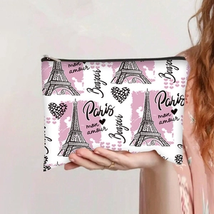 Detailed view of canvas makeup bag with Eiffel Tower print held by hand for size scaling