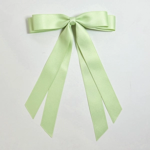 Macro view of mint green double-layered satin bow hair clip with long silk ribbons