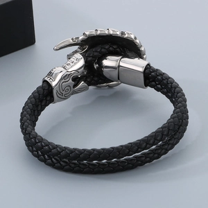 Black braided leather bracelet with stainless steel dragon head clasp on neutral background