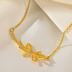 Detailed close-up of golden bow pendant with twisted texture and sparkling crystals