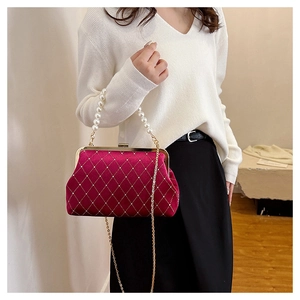 Detail view of red velvet shell bag with diamond quilt pattern and pearl handle