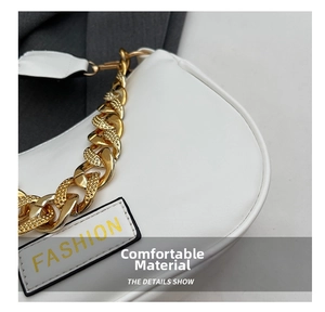 Close-up of a white leather underarm bag featuring a chunky gold chain and fashion tag