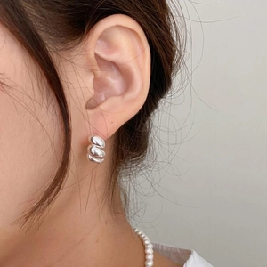 Close-up of minimalist sterling silver twisted rope stud earring worn on the earlobe