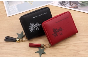 Detail of mini zip wallets in black and red PU leather with lychee texture and tassels