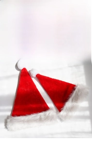 Close-up of classic red plush Christmas hats with soft white faux fur trim and pompom