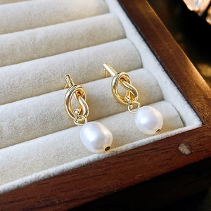 Détail macro de boucles d'oreilles nœud doré avec perles d'eau douce dans un écrin