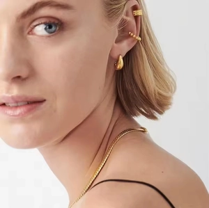 Dettaglio di orecchini a goccia in oro 18K e collana a catena piatta su modella