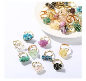 Primer plano de anillos de piedras naturales envueltos en hilo dorado sobre plato blanco