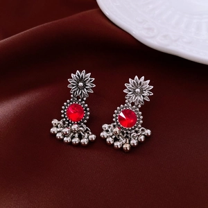 Detail of vintage silver earrings with ruby red stones on velvet background