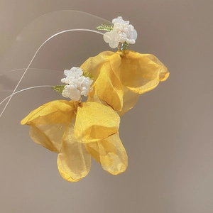 Close-up of yellow tulle flower earrings with intricate white seed bead floral details