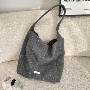 Dettaglio borsa shopper in lana con stelle bianche su divano bianco bouclé per autunno