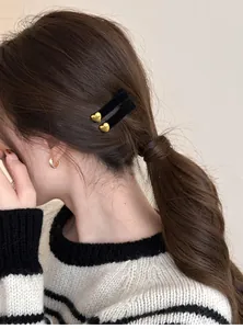 Dettaglio di un piccolo fermaglio per capelli in velluto nero con cuore dorato