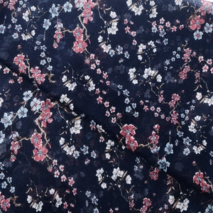 Close-up of navy blue floral scarf fabric with pink cherry blossom pattern and texture