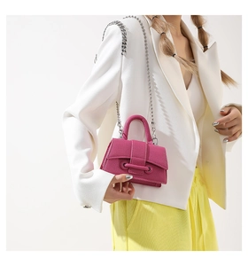Close-up of fuchsia textured leather mini bag with silver chain strap worn by a model