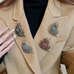 Detailed macro view of four hollow horse brooches with colorful rhinestones on a coat