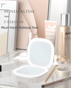 Detail of white portable LED makeup mirror with touch sensor on a minimalist tray