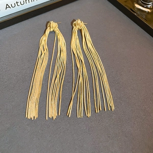 Detail view of gold tassel knot earrings with sparkling cubic zirconia on grey background