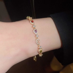 Close-up of a golden bracelet with multi-colored pear-cut zircons on a model's wrist