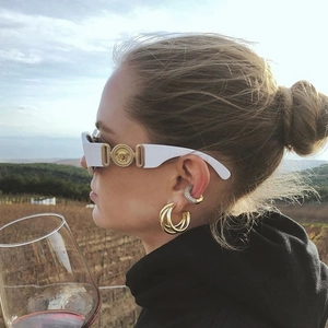 Gros plan de boucles d'oreilles créoles dorées à trois rangs et manchette en diamant