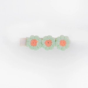Detail of three green embroidered flowers on a ribbon-wrapped hair clip for girls