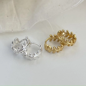 Vue macro de boucles d'oreilles feuille d'olivier en argent S925, finitions or et argent