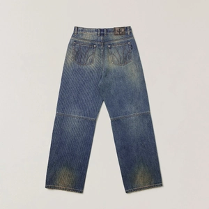 Detail of vintage blue washed denim jeans featuring distressed texture and cross leather patch